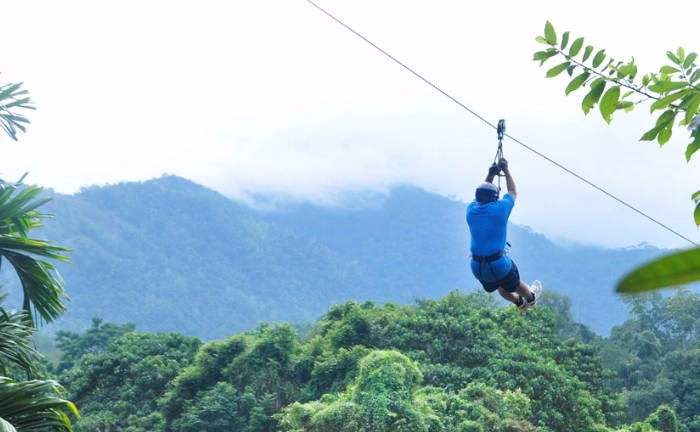 Adventurer soaring on the 350-meter zip lining above the Kelani River in Kitulgala